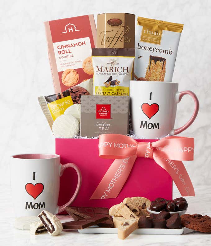A Mother's Day gift basket containing Chocolate Chip Biscotti, Brownie Cookies, Mom Mug, Honeycomb Chocolate Bar, French Truffles, White Chocolate Covered Sandwich Cookies, Dark Chocolate Sea Salt Cashews, and Earl Grey Tea, beautifully presented with a p