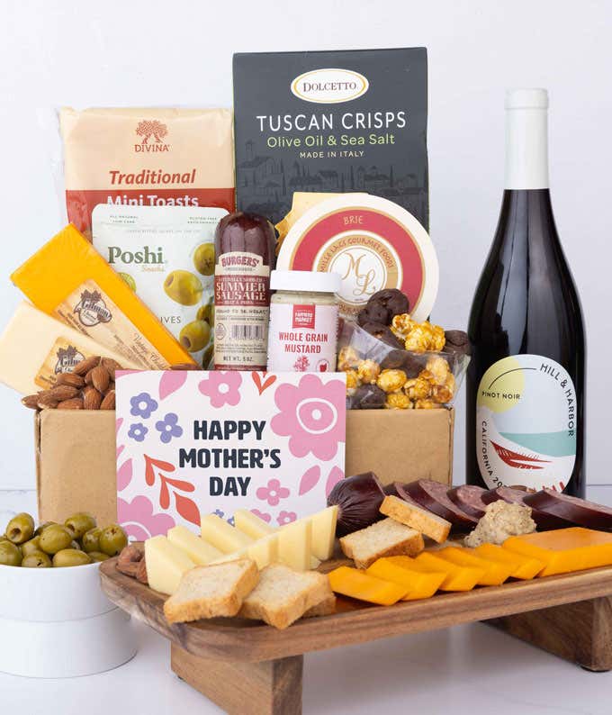 A charcuterie spread with 3 cheeses, summer sausage, olives, crackers, mustard, almonds, and chocolate treats finished with a bottle of Pinot Noir and 'Happy Mother's Day' card.