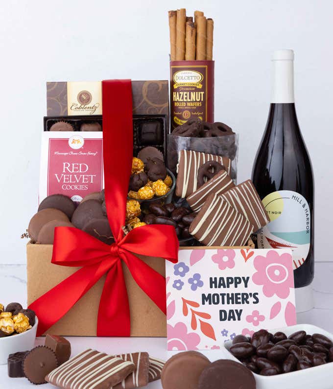 A bottle of Hill & Harbor Pinot Noir sits beside chocolate-covered pretzels, mini chocolate chip cookies, caramel popcorn, assorted chocolates, mini buckeyes, chocolate covered Oreos, and a Happy Mother's Day card.