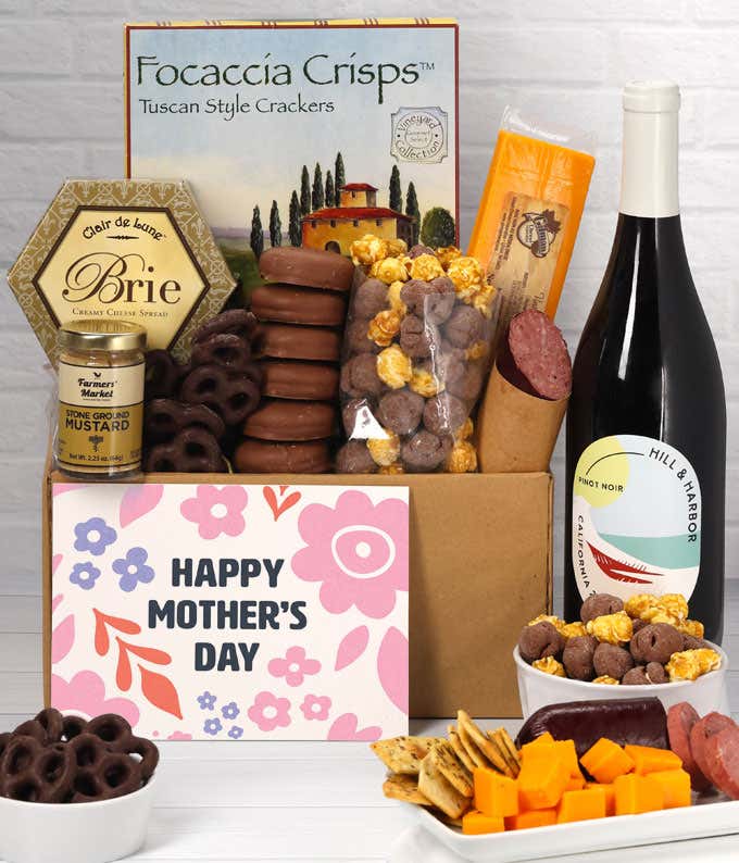 A spread featuring Hill & Harbor Pinot Noir, 2 cheeses, summer sausage, crackers, chocolate pretzels, caramel corn, and chocolate covered Oreos with a 'Happy Mother's Day' card.