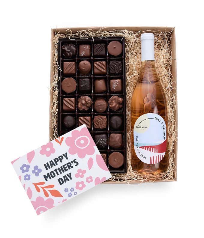 A gift box with Hill & Harbor Rosé wine and a 1 lb. box of assorted artisan chocolates with a 'Happy Mother's Day' card placed on top.
