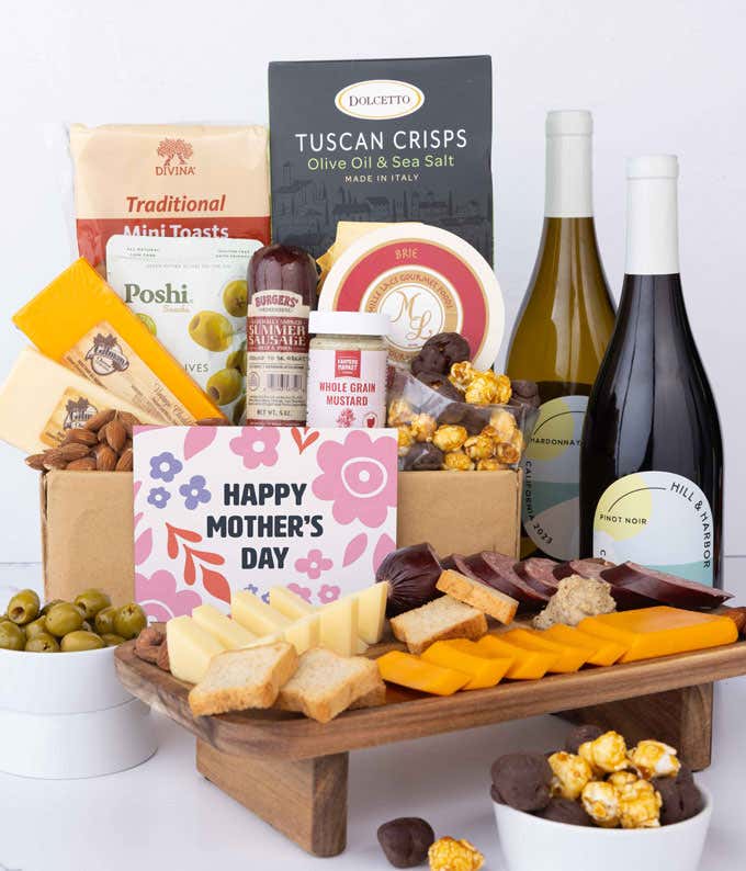A charcuterie spread with 3 cheeses, sausage, olives, crackers, mustard, almonds, and chocolate finished with bottle of red & white wine and 'Happy Mother's Day' card.