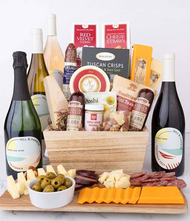 Wooden basket filled with 4 cheeses, 3 sausages, crackers, cookies, nuts, mustard, olives and crisps alongside 4 bottles of wine - Pinot Noir, Chardonnay, Ros&eacute; &amp; Sparkling Wine.